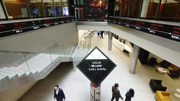 Employees walk past share price information for British Land Plc displayed on an illuminated rotating cube in the atrium of the London Stock Exchange Group Plc's offices in London, U.K., on Wednesday, May 29, 2019. While the FTSE 100 Index has climbed about 15 percent since June 2016 in local currency, it's down in both euro and dollar terms. 