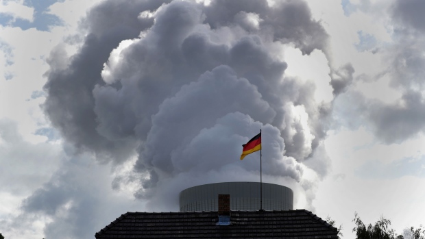 A German national flag flies from a residential property in front of emissions issuing from a cooling at the Schwarze Pumpe lignite fueled power plant, operated by Lausitz Energie Bergbau AG (LEAG), in Spremberg, Germany, on Friday, Aug. 16, 2019. Government plans to exit coal-fired power generation by 2038 have enraged voters already stirred up by a wave of immigration in 2016. 