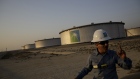 An employee walks past crude oil storage tanks at the Juaymah Tank Farm in Saudi Aramco's Ras Tanura oil refinery and oil terminal in Ras Tanura, Saudi Arabia, on Monday, Oct. 1, 2018. Saudi Arabia is seeking to transform its crude-dependent economy by developing new industries, and is pushing into petrochemicals as a way to earn more from its energy deposits. 