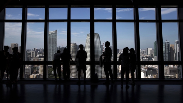 Visitors are silhouetted as they look out of windows at an observatory in the central business district of Tokyo, Japan, on Wednesday, June 27, 2018. The Bank of Japan's (BOJ) Tankan quarterly business survey for June, scheduled to be released on July 2, is likely to show concerns about U.S. tariffs putting a dent in business sentiment. 