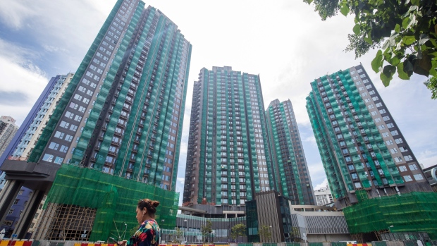 Residents walk past a residential construction site in the Yuen Long district of the New Territories in Hong Hong, China, on Tuesday, July 23, 2019. A rally of more than 100,000 people in Hong Kong devolved into a night of violence on Sunday, with police firing tear gas after protesters gathered in front of China's liaison office in the city and defaced the national emblem. Masked men wearing white shirts and wielding batons, some suspected to be linked to triads, later attacked people in a metro station and mall in the mainland border town of Yuen Long. 