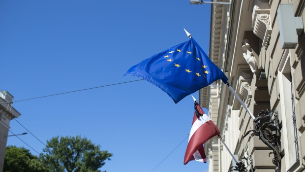 The Latvian national flag, left, and the European Union (EU) flag fly outside the Latvian central bank, also known as Latvijas Banka, ahead of the European Central Bank (ECB) rate decision in Riga, Latvia, on Thursday, June 14, 2018. European Central Bank President Mario Draghi and his colleagues will hold their first formal talks on Thursday on when to end their asset purchase program, though it's less clear whether they'll make a decision or wait until July. 
