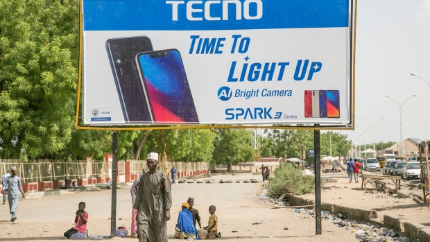Pedestrians walk past a roadside billboard advertising Spark smartphone handsets by Tecno Mobile in Maiduguri, Nigeria, on Wednesday, May 1, 2019. Nigeria will propose a supplementary budget later this year to boost capital spending and fund a 67 percent increase in the minimum wage as government revenues improve, Budget Minister Udo Udoma said. 