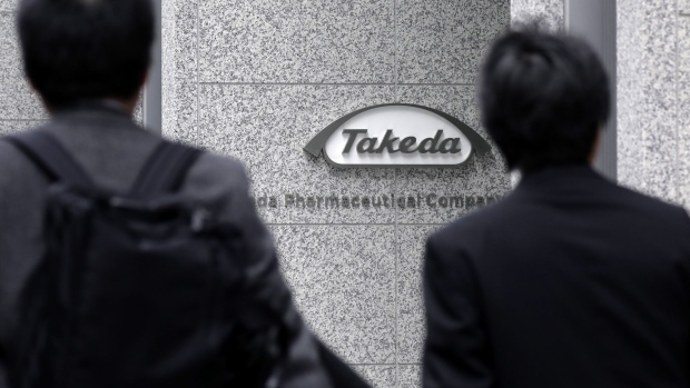 Pedestrians walk past the Takeda Pharmaceutical Co. global headquarters in Tokyo, Japan, on Wednesday, Dec. 5, 2018. Takeda received shareholder approval for its $62 billion acquisition of U.K.-listed Shire Plc, an endorsement of Chief Executive Officer Christophe Weber’s strategy to transform the Japanese drugmaker into a global powerhouse. 