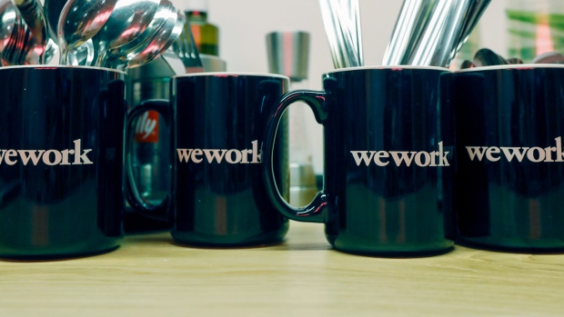 Cutlery stands in WeWork Cos. branded mugs in a kitchen area in the WeWork Cos. co-working space at the One Poultry building in the City of London, U.K., on Wednesday, Oct. 3, 2018. Hana Financial Group Inc. is in talks to buy the building, best known for its stripes of pink and yellow limestone, that has been transformed into a major WeWork Cos. co-working space. 