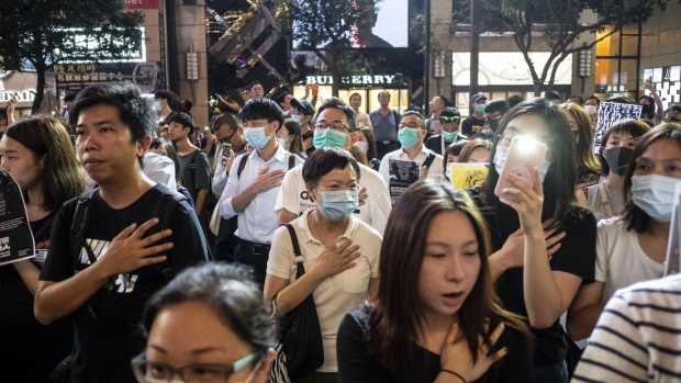 Demonstrators put hands over their hearts during a protest in Causeway Bay on Oct. 2. Photographer: Chan Long Hei/Bloomberg