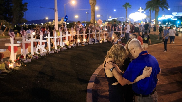 A small group prays at a makeshift memorial with 58 white crosses, one for each victim, on the south end of the Las Vegas Strip, October 6, 2017 in Las Vegas.