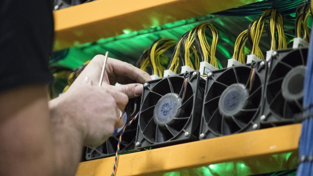 An employee changes the fan on a mining machine at the Bitfarms cryptocurrency farming facility in Farnham, Quebec, Canada, on Wednesday, Jan. 24, 2018. Bitfarms says it's making more than $250,000 a day from minting Bitcoin, other virtual currencies and fees at four sites in the province. 