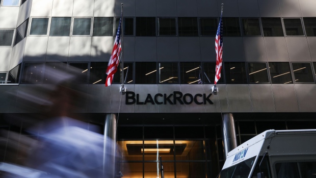 A pedestrian walks past American flags flying at BlackRock Inc. headquarters in New York, U.S, on Wednesday, June 11, 2018. BlackRock Inc. is scheduled to release earnings figures on July 16. 