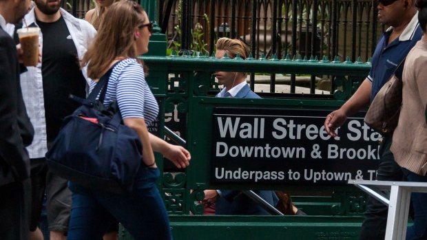 Pedestrians pass the Wall Street subway station near the New York Stock Exchange. 
