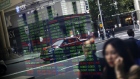 Pedestrians are reflected in a window as they walk past an electronic stock board at the ASX Ltd. exchange centre in Sydney, Australia, on Thursday, Feb. 14, 2019. “We made good progress on our core initiatives across the period, including the program to replace CHESS with distributed ledger technology; upgrade of our secondary data centre to strengthen market resilience; and restructure of our Listings Compliance team to enhance the quality of market oversight,” ASX Chief Executive Officer Dominic Stevens said. 