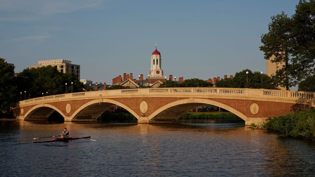A sculler rows on the Charles River past the Harvard University campus in Cambridge, Massachusetts, U.S., on Tuesday, June 30, 2015. Harvard University, established in 1636, is the United States' oldest institution of higher learning. 