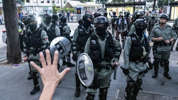 A demonstrator holds up his hand in front of riot police at Statue Square the day after the government announced the newly imposed ban on masks in the Central district of Hong Kong, China, on Saturday, Oct. 5, 2019. Hong Kong went into near shutdown as businesses closed and rail services were suspended for the first time in more than 20 years after overnight violence described by Chief Executive Carrie Lam as a very dark day. 
