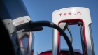 A Tesla Inc. charging station sits connected to an electric automobile at a Tesla Supercharger stati