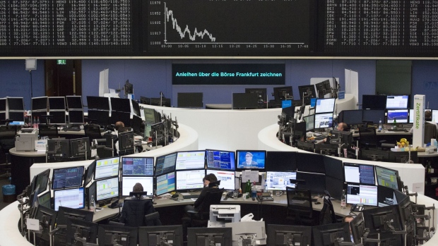 Traders monitor financial data as the DAX index curve is displayed beyond inside the Frankfurt Stock Exchange, operated by Deutsche Boerse AG, in Frankfurt. 