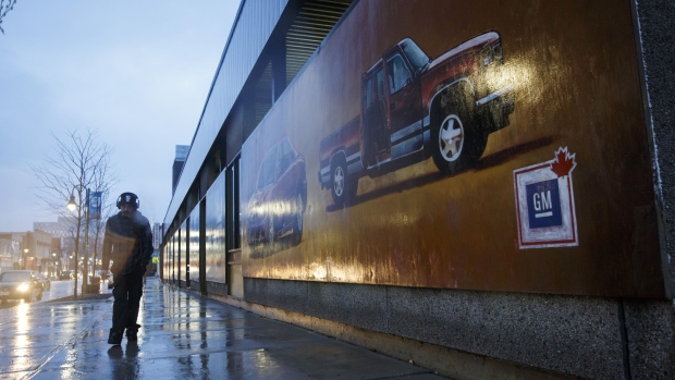 A pedestrian walks past a General Motors Co. mural depicting in downtown Oshawa, Ontario, Nov. 26, 2