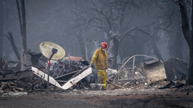 A firefighter searches a burned-out building in Paradise, California, U.S., on Thursday, Nov. 15, 2018. The number of acres burned in the blazes -- including the Hill and Woolsey fires in Southern California, and the Camp fire in Northern California, which has killed at least 48 people and destroyed the city of Paradise -- already is higher than the total burned in wildfires last year, A.M. Best Co. wrote in a report late Tuesday. 