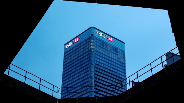 Logos sit illuminated on the HSBC Holdings Plc headquarter skyscraper offices in the Canary Wharf business, financial and shopping district in London, U.K., on Tuesday, May 2, 2017. HSBC has appeased investors with $3.5 billion of share buybacks, but after five years of declining revenue analysts are looking for evidence the bank is stabilizing its top line when it reports earnings Thursday. 