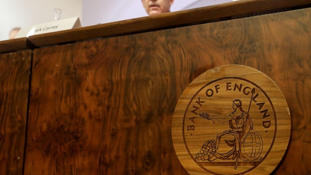 A wooden plaque of the Bank of England (BOE) logo sits on a desk as Mark Carney, governor of the Bank of England (BOE), speaks at the bank's quarterly inflation report news conference in the City of London, U.K., on Thursday, Aug. 1, 2019. The BOE said it's less confident than usual about the outlook for the economy because of Brexit and offered little new insight into the impact of no deal. 