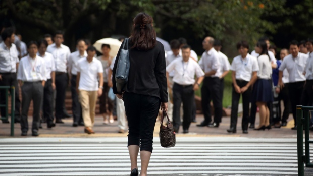 A woman waits to cross a road in the Kasumigaseki area of Tokyo, Japan, on Thursday, Sept. 11, 2014.