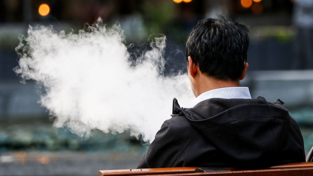 A pedestrian exhales a cloud of vapour from a vape device in London. 