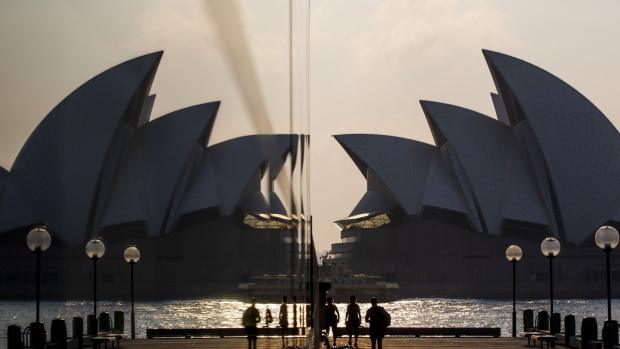 People are reflected in a surface as they walk near the Sydney Opera House in Sydney, Australia, on Friday, Nov. 1, 2019. Australia is bracing for more devastating bushfires, with swaths of the eastern seaboard and even areas of greater Sydney facing a "catastrophic" threat that's unprecedented at this time of year. 