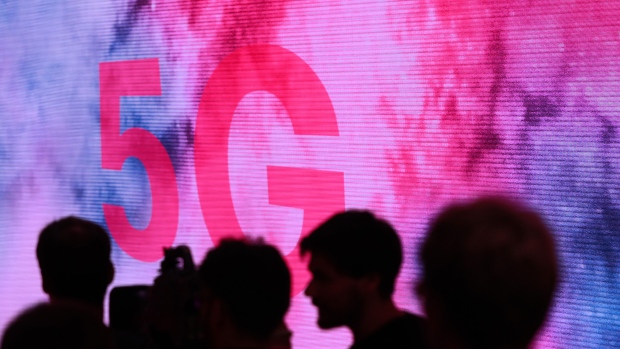 Attendees are silhouetted beside a 5G display on the Deutsche Telekom AG exhibition area during a press preview day at the IFA consumer electronics show in Berlin, Germany, on Thursday, Sept. 5, 2019. The IFA tech show runs from Sept. 6 - 11. 