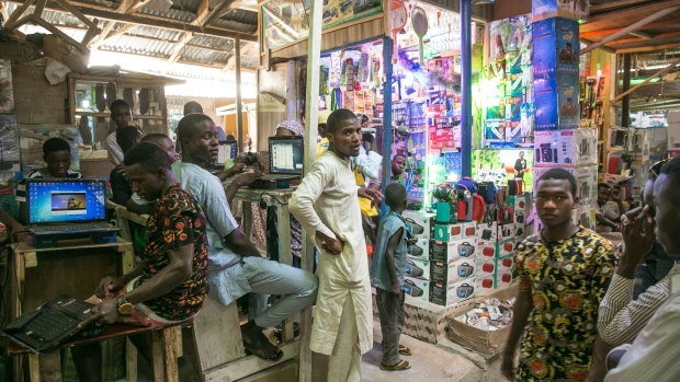 A vendor displays electronic goods for sale at a kiosk as people work at laptop computers inside Jagwal Electronics Market in Maiduguri, Nigeria, on Wednesday, May 1, 2019. Nigeria will propose a supplementary budget later this year to boost capital spending and fund a 67 percent increase in the minimum wage as government revenues improve, Budget Minister Udo Udoma said. 