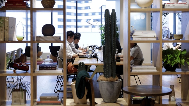 Members sit around a communal working table inside the WeWork office space in Yokohama, Japan. 