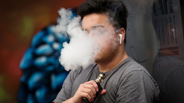 A person exhales vapor while using an electronic cigarette device. 