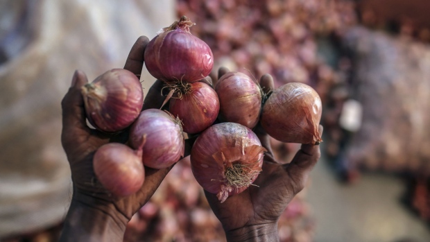 A worker holds onions at a market in Mumbai, India. Bloomberg/Dhiraj Singh