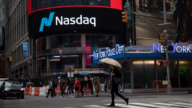 A pedestrian holds an umbrella while crossing the street front of the Nasdaq MarketSite in the Times Square area of New York, U.S., on Friday, Sept. 6, 2019. U.S. stocks advanced and Treasuries were mixed as Federal Reserve Chairman Jerome Powell’s latest comments did little to alter views on Federal Reserve policy. 