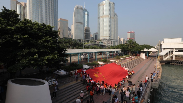 Pro-government supporters display a Chinese flag during a flash mob in the Central district of Hong Kong, China, on Tuesday, Oct. 1, 2019. Chinese President Xi Jinping stressed national unity and said relations between Hong Kong and the mainland would improve, as the city braced for a wave of protests to coincide with the 70th anniversary of Communist rule. 