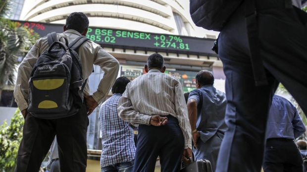 People look toward a screen and an electronic ticker board outside the Bombay Stock Exchange (BSE) building in Mumbai, India, on Thursday, May 23, 2019. Indian Prime Minister Narendra Modi is set to win a majority on his own in India’s general election, with his Bharatiya Janata Party surging to a commanding lead in early vote counting. 