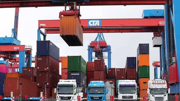 Shipping containers are loaded onto cargo trucks, manufactured by Man SE and Scania AB, right, as Germany's Chancellor Angela Merkel, not pictured, visits the HHLA Container Terminal Altenwerder (CTA) in the port of Hamburg in Hamburg, Germany, on Monday, May 6, 2019. Merkel said Germany needs to stand up for multilateral agreements and strengthening the World Trade Organization in the face of recent “protectionist tendencies.” 