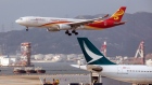 A Hong Kong Airlines Ltd. aircraft prepares to land as an Airbus A330 aircraft operated by Cathay Pacific Airways Ltd. sits parked at Hong Kong International Airport in Hong Kong, China, on Tuesday, March 5, 2019. Cathay is in talks to buy shares in Hong Kong’s only budget airline Hong Kong Express from Chinese conglomerate HNA Group Co., as Asia’s biggest international carrier seeks to gain a foothold in the region’s booming low-cost travel market. 