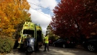 A worker loads household waste containers into a GFL Environmental Inc. garbage truck