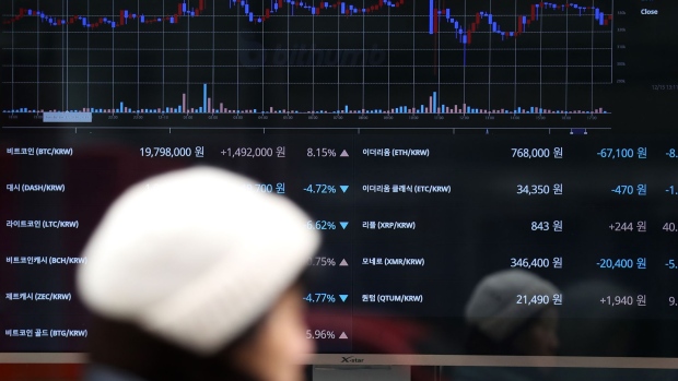 A pedestrian walks past a monitor showing the prices of virtual currencies at the Bithumb exchange office in Seoul, South Korea. 