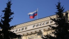 A Russian national flag flies above the headquarters of Bank Rossii, Russia's central bank, in Moscow, Russia, on Friday, Dec. 11, 2015. Russia's central bank left its benchmark interest rate unchanged for a third consecutive meeting as a slump in oil prices triggered a new bout of ruble weakness, raising the risk of faster inflation. 