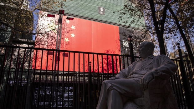 A statue of former Chinese leader Mao Zedong stands on display near a Chinese flag at the Yema Group headquarters in Urumqi, Xinjiang autonomous region, China, on Tuesday, Nov. 6, 2018. Although it represents just 1.5 percent of China's population and 1.3 percent of its economy, Xinjiang sits at the geographic heart of Xi's signature Belt and Road Initiative. Source: Bloomberg/Bloomberg