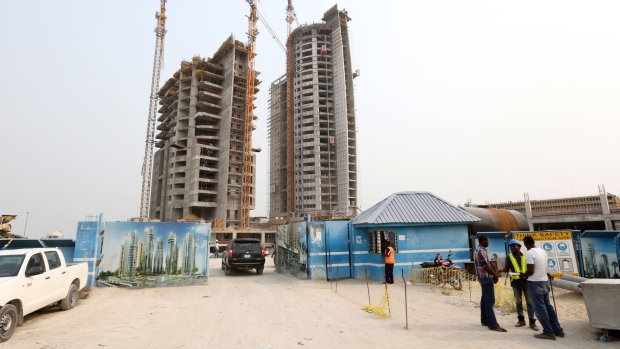 Workers stand outside the site entrance for the Eko Pearl Towers residential development at the Eko Atlantic city site in Lagos. Photographer: George Osodi/Bloomberg