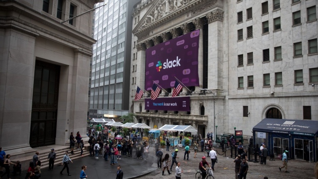 Pedestrians pass in front of a Slack Technologies Inc. signage displayed outside of the New York Stock Exchange (NYSE) during the company's initial public offering (IPO) in New York, U.S., on Thursday, June 20, 2019. 