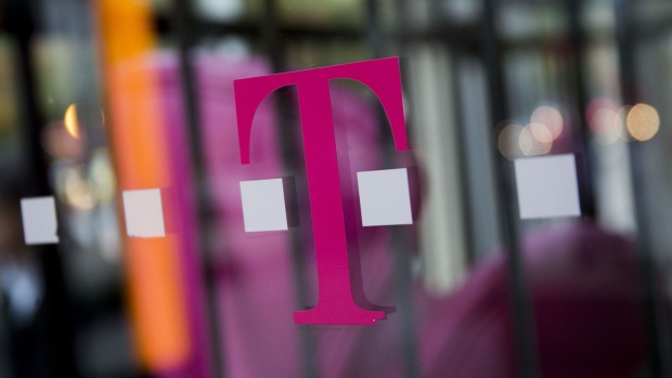 A T-Mobile US Inc. logo hangs in the window at a retail store in Washington, D.C., U.S., on Thursday, Oct. 23, 2014. 