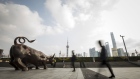 Pedestrians walk past the Bund Bull statue as skyscrapers of the Pudong Lujiazui Financial District stand across the Huangpu River in Shanghai, China, on Friday, Dec. 28, 2018. China announced plans to rein in the expansion of lending by the nation's regional banks to areas beyond their home bases, the latest step policy makers have taken to defend against financial risk in the world's second-biggest economy. Photographer: Qilai Shen/Bloomberg