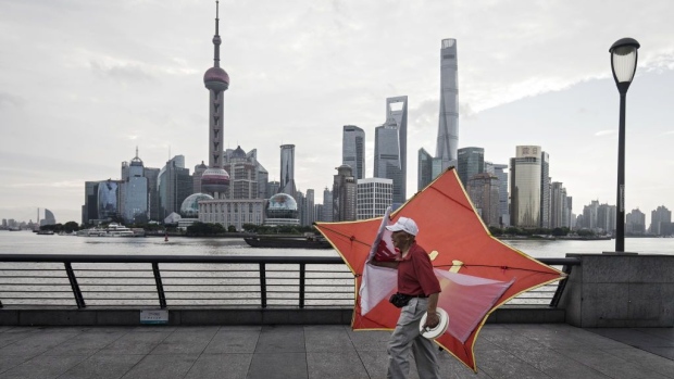 A man carries a kite along the bund as the Lujiazui Financial District stands in the background in Shanghai, China, on Monday, Sept. 4, 2017. The Chinese central bank's tight leash on liquidity is straining the bond market, with the benchmark sovereign yield climbing to near the highest level since April 2015. Photographer: Bloomberg/Bloomberg