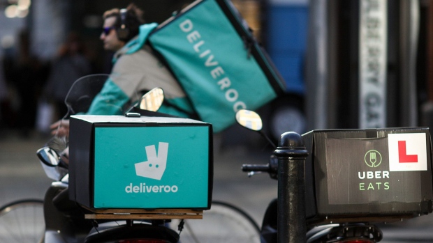 A food delivery cycle courier, working for Deliveroo, operated by Roofoods Ltd., passes motor scooters with boxes for Deliveroo, left and center, and UberEats, operated by Uber Technologies Inc., right, in London, U.K., on Thursday, Dec. 22, 2016. The food delivery business model has proven attractive to venture capitalists, who last year poured $5.5 billion into food-delivery companies globally, according to research firm CB Insights. Photographer: Simon Dawson/Bloomberg