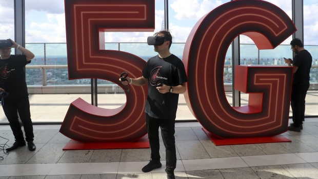 A man uses a virtual-reality headset in front of a 5G logo during the launch of Vodafone Group Plc's 5G wireless network in London, U.K., on Wednesday, July 3, 2019. Vodafone switched on the U.K.'s second 5G wireless network on Wednesday, kicking off a commercial battle with dominant rival EE that could shape a decade of sales. Photographer: Simon Dawson/Bloomberg