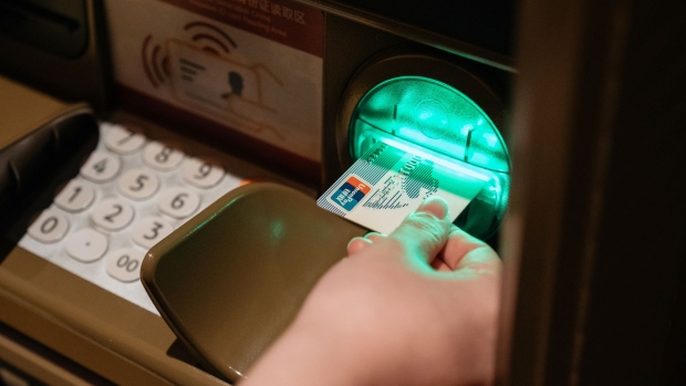 A woman inserts a China UnionPay Co. card at an automated teller machine (ATM) equipped with facial-recognition software in an arranged photograph taken in Macau, China, on Thursday, May 25, 2017. Chinese bettors withdrawing money from some ATMs in Macau need to do more than punch in their PIN code. They also have to stare into a camera for six seconds so facial-recognition software can verify their identity and help monitor transactions. Photographer: Billy H.C. Kwok/Bloomberg