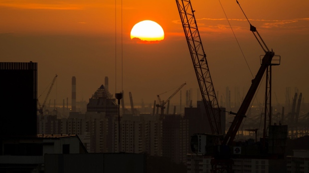 A crane standing at the construction site is silhouetted as sun sets in the background in Singapore, on Thursday, Sept. 15, 2016. Singapore is currently mired in its most prolonged housing slump on record. Home prices in the city-state fell for the 11th straight quarter in the three months ending June 30, posting the longest losing streak since records started in 1975. Photographer: SeongJoon Cho/Bloomberg
