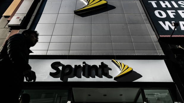 A pedestrian talks on a mobile phone while walking past a Sprint Corp. store in Washington, D.C., U.S., on Friday, Oct. 24, 2014.
